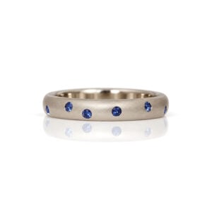 A Platinum ring with blue sapphires flush set around randomly David Ashton London